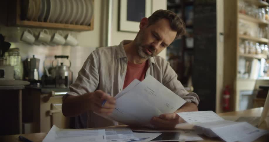 A man sits at home and goes through paperwork