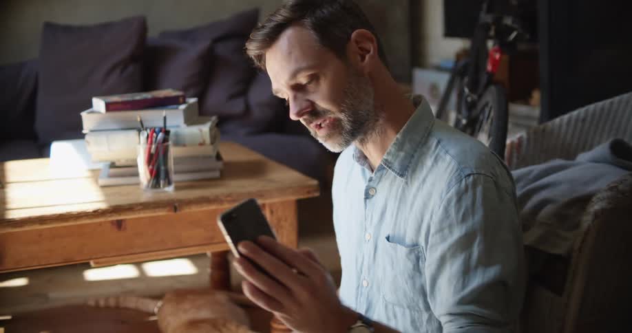 A man is talking on his phone and showing his cat
