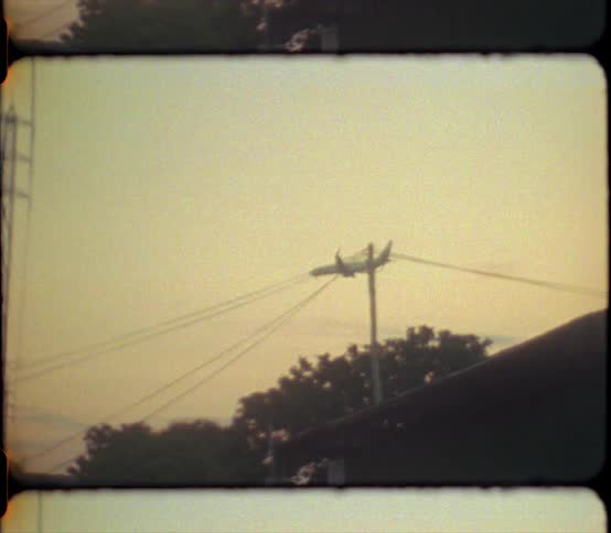 Vintage film of a commercial airplane flying overhead at evening