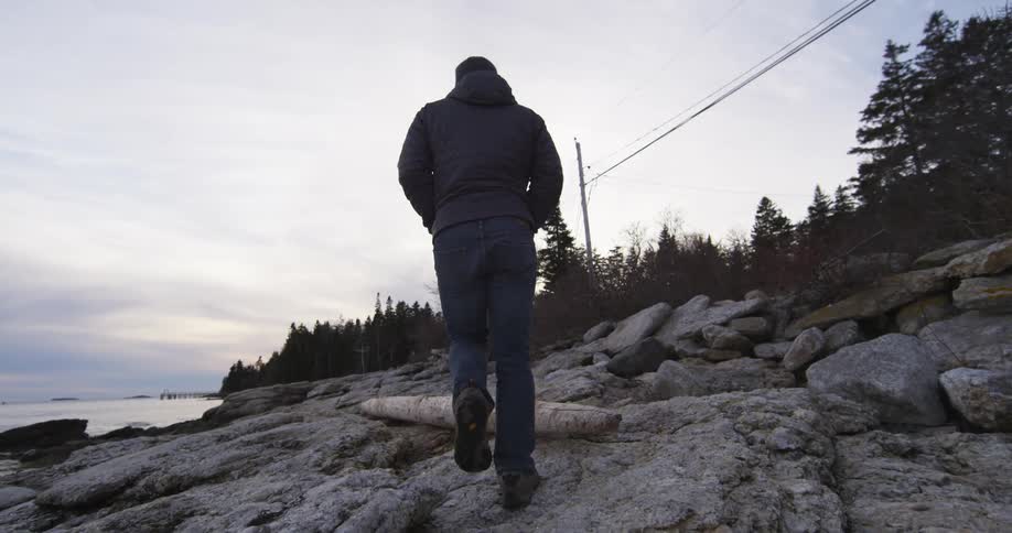 A man is walking uphill by the shore