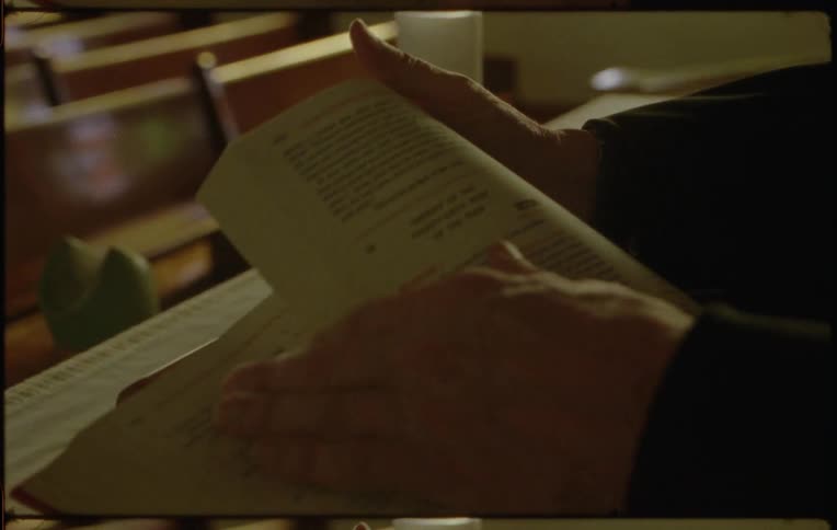 A person opens a lectionary on a lectern in a church during the day