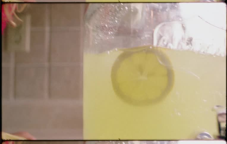 Young blonde girl preparing a jar of lemonade over the kitchen counter top at home