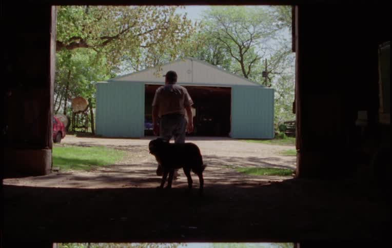 A man and his dog walking out of a barn