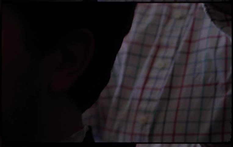 A man adjusts settings on electric hair clippers and starts cutting someones hair indoors