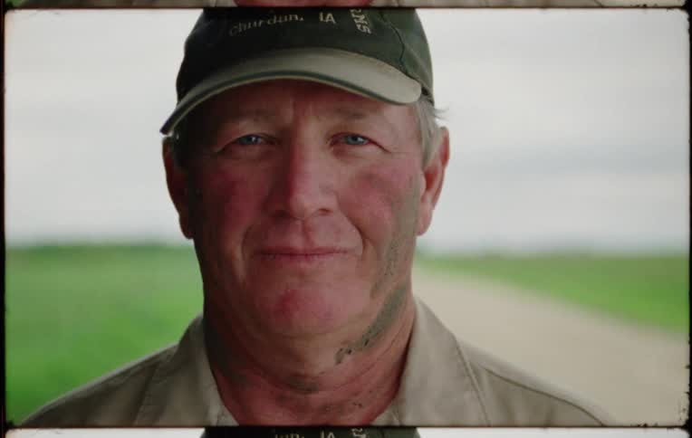 Mature man wearing a baseball cap with dirt on his face looks at the camera