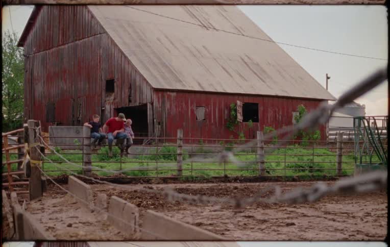 Father sitting with his siblings over a fence near a red barn in a farm at daytime