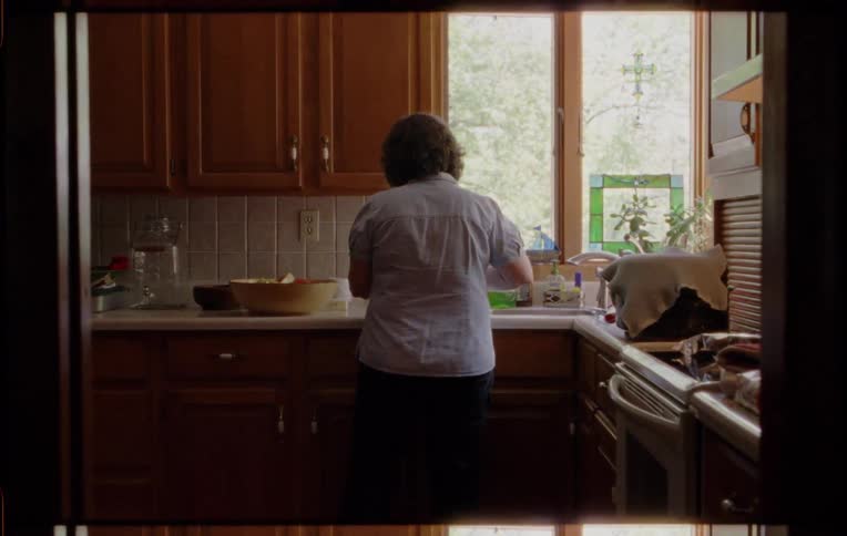 A woman in the kitchen cutting watermelon with a knife
