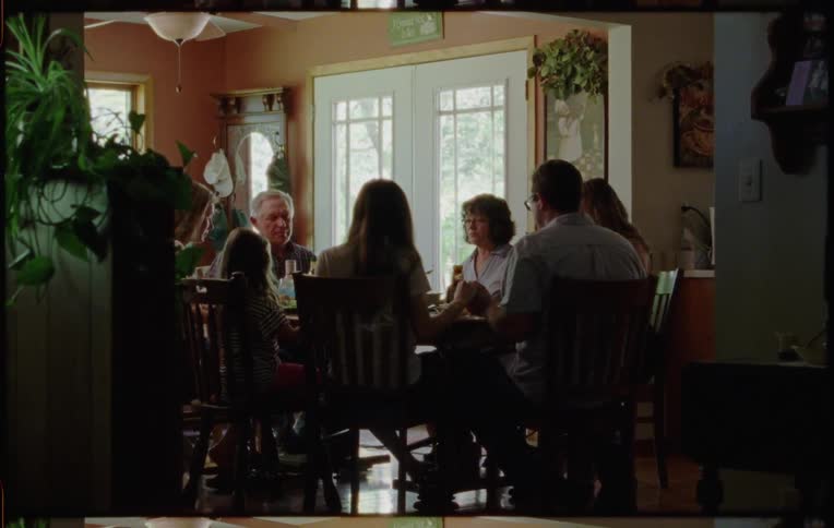 Family sitting at the table at home hold hands in prayer before lunch