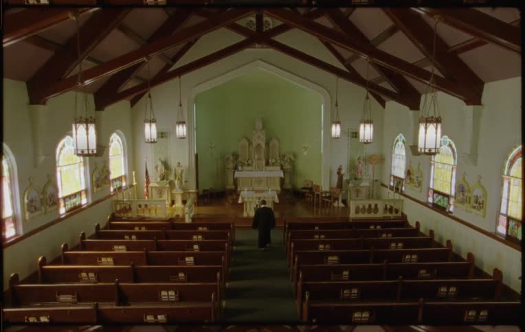 Film footage of a priest walking to the front of a church