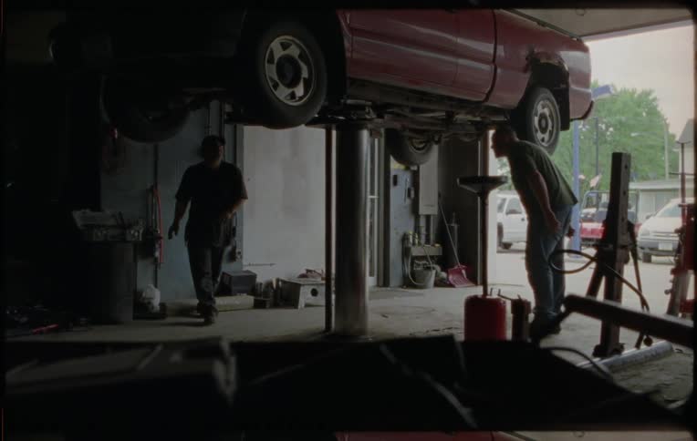 Two men are working on a car in a mechanic shop