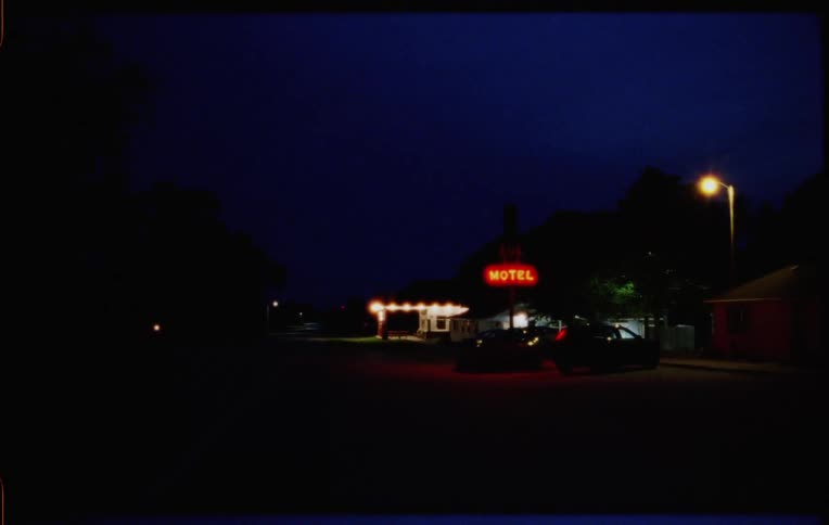 The parking lot of a motel next to a road at night