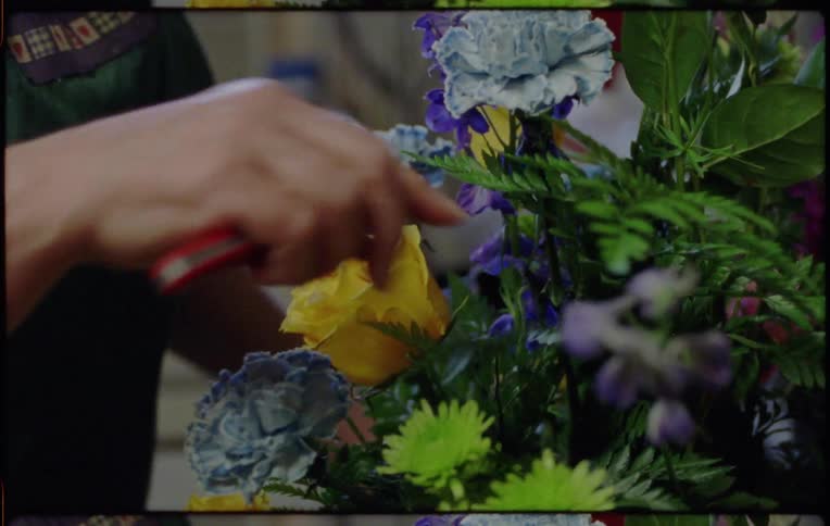 A woman in a shop puts together a floral arrangement