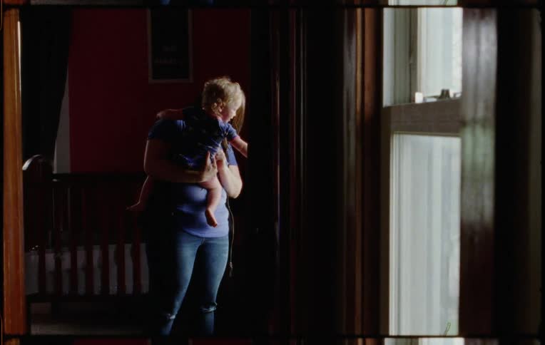 A mother is holding her daughter in the hallway