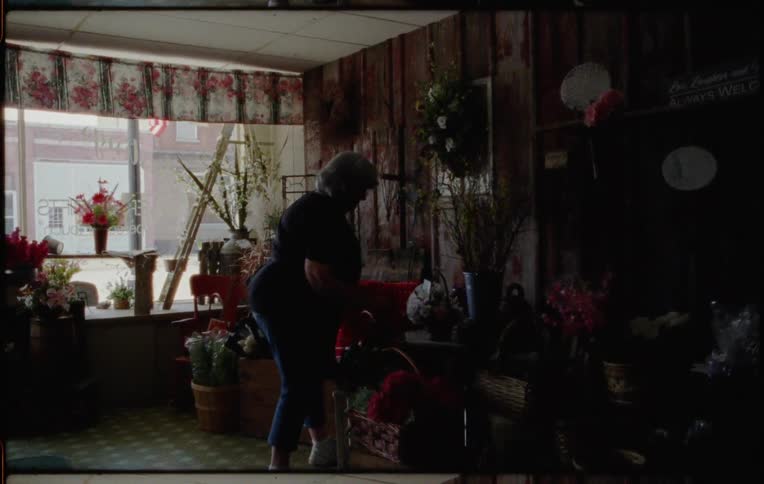 A woman in a store hangs a wreath on a wall