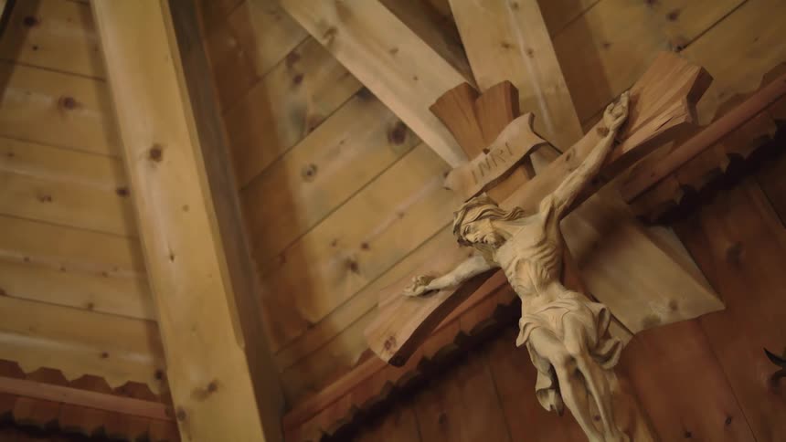 Wooden crucifix hanging on the wooden wall inside a church