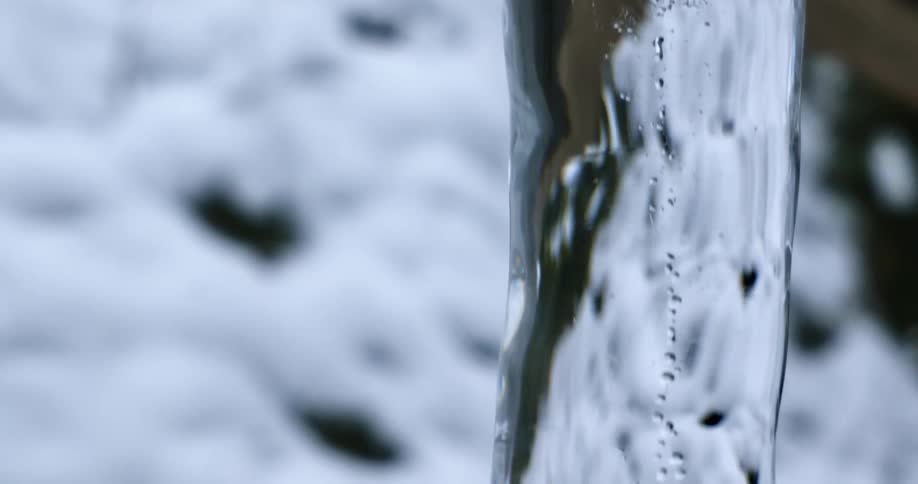 An icicle hangs from a metal pole above snow covered ground