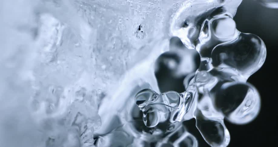 Water flows over ice causing it to shimmer and reflect