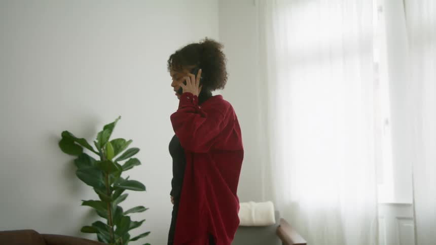A woman walks around her home as she talks on the phone