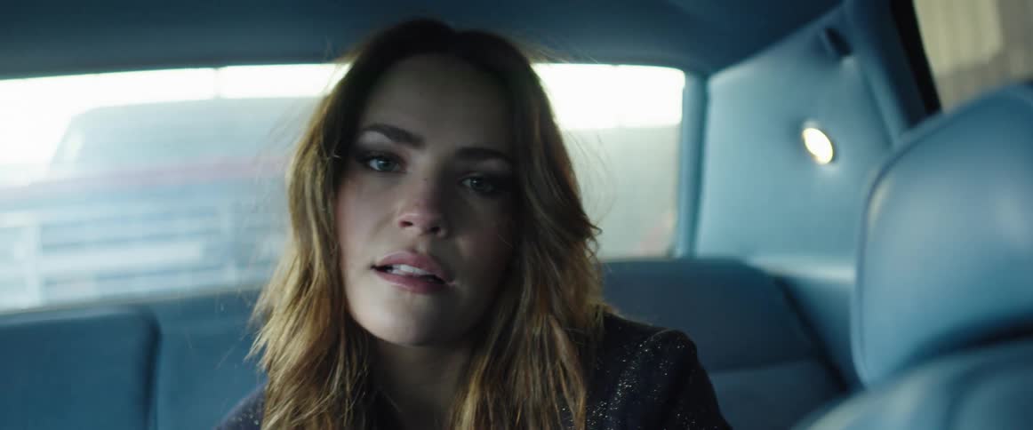 Young woman modeling inside a car looks at the camera