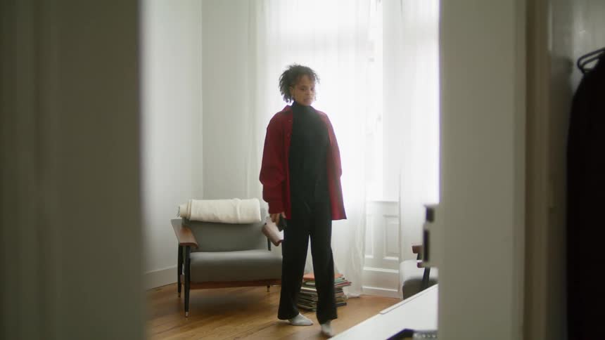 A woman pacing around a room checking her phone