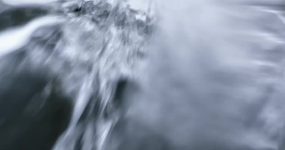 A thick stream of water rushes over a waterfall