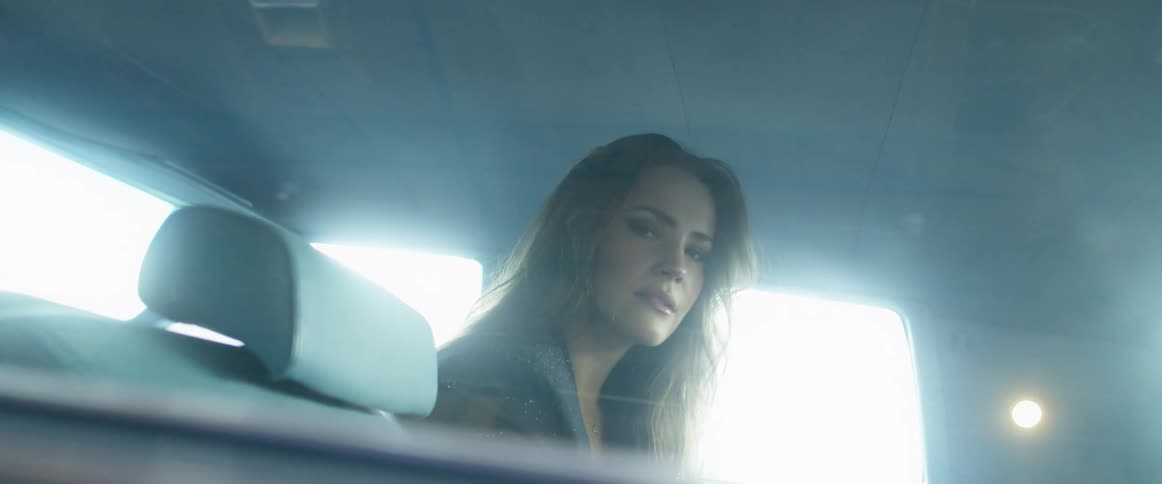 Woman sits in bobbing vehicle backlit by light from window