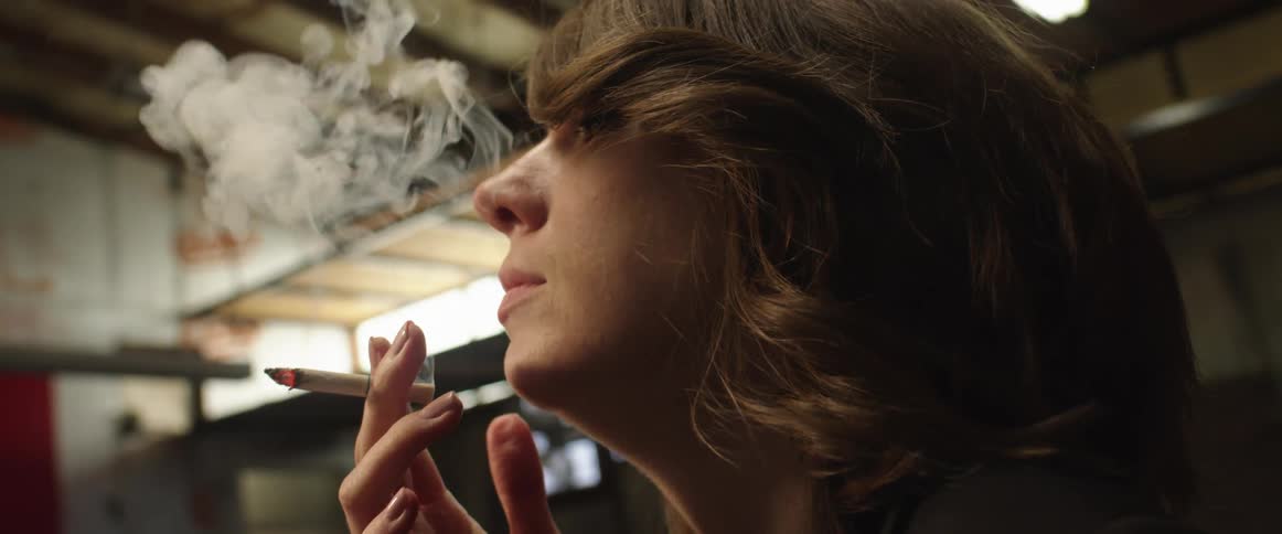 Woman in warehouse blows smoke