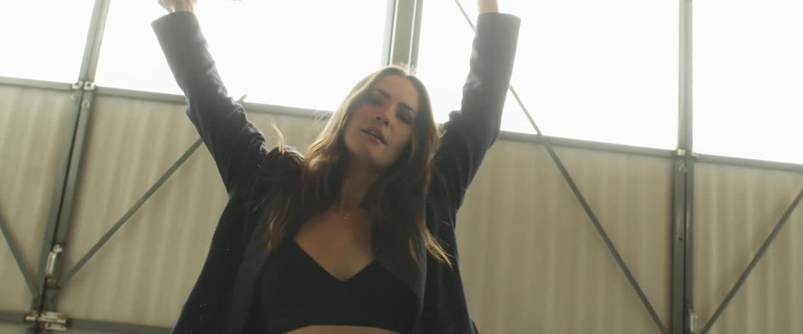 Woman stretches and poses standing in building near car