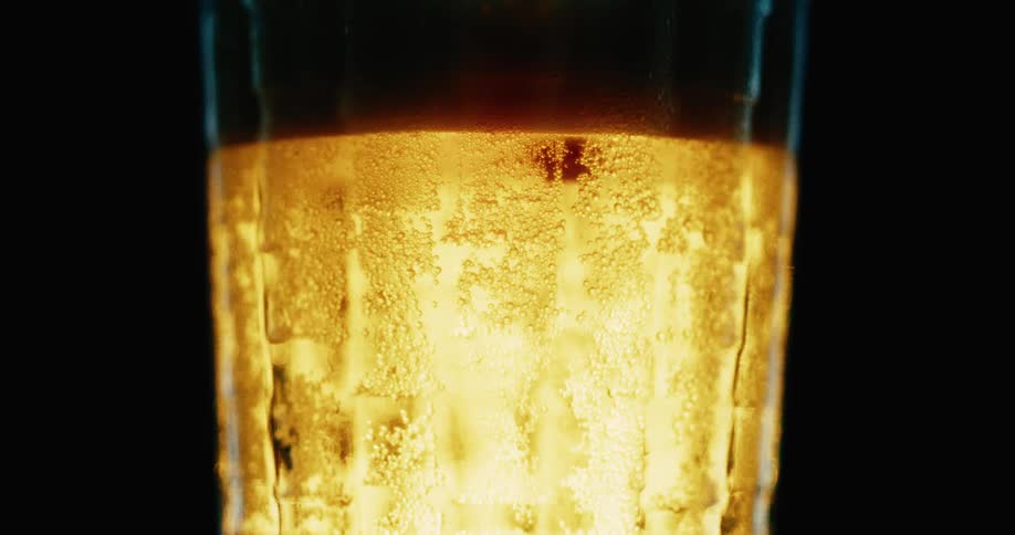 Silhouette of a hand picking up a glass of freshly poured beer