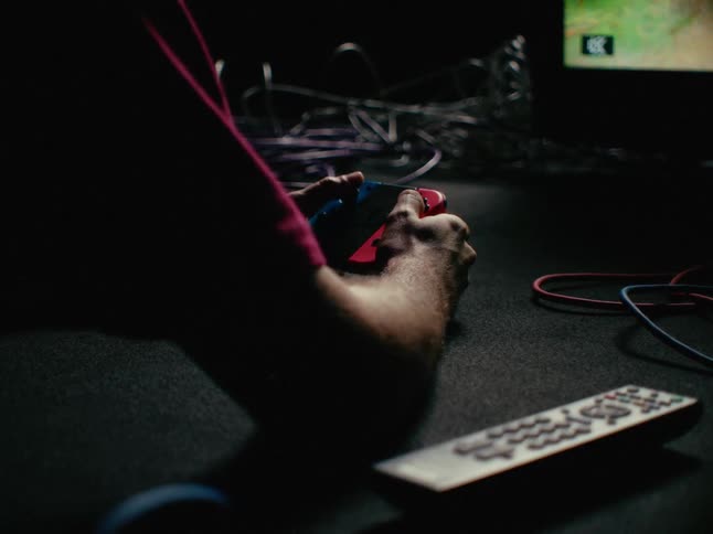 A person on the floor of a room playing video games on a television with a control