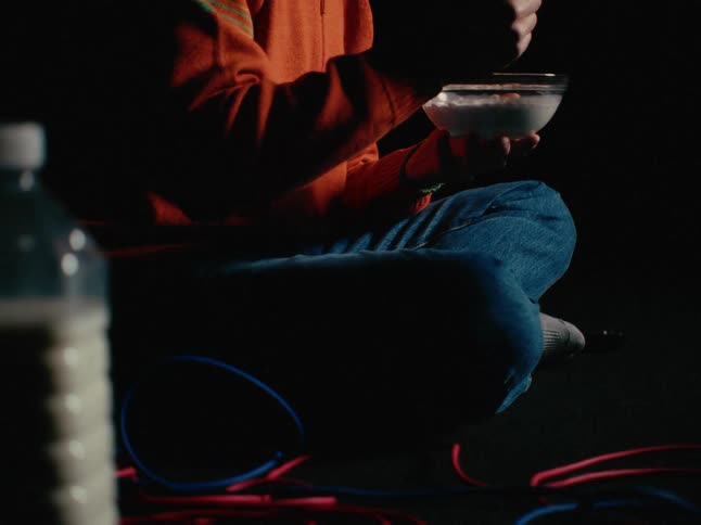 A man is sitting and eating a bowl of cereal
