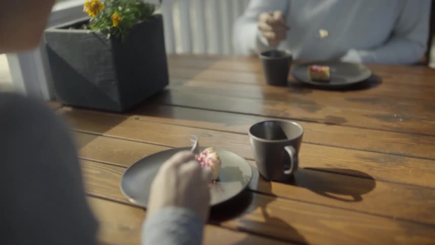 Two people sit eating dessert at an outdoor table