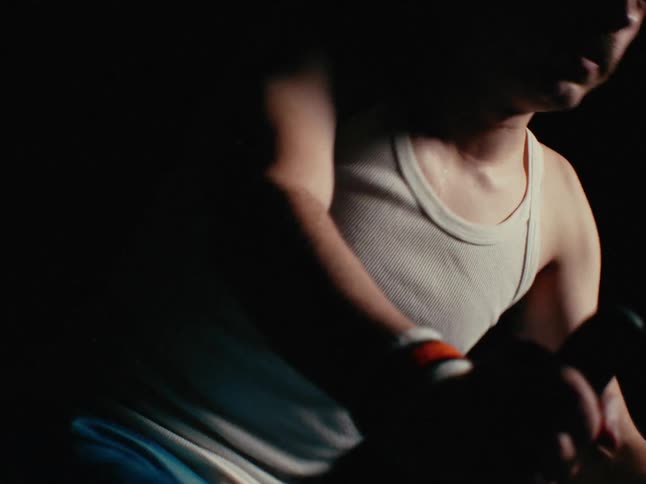 A man in a tank top pedals hard on a stationary bike before slowing down to catch his breath