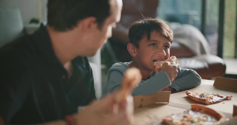 Father and son bonding while enjoying pizza in living room