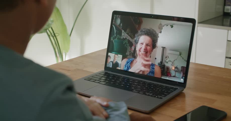 Family happily smiles while talking via laptop