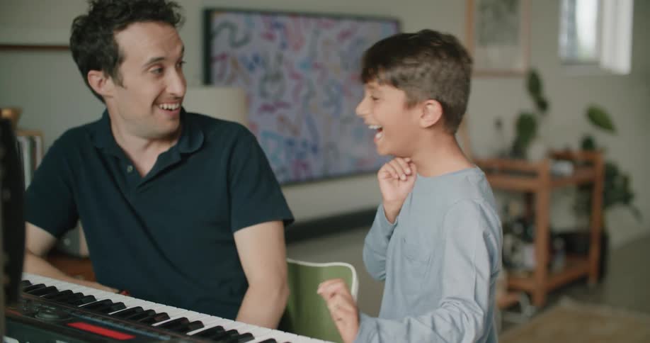 A father and son playing piano together