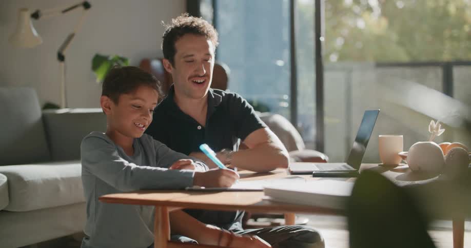A man and a boy sitting next to a table with a laptop