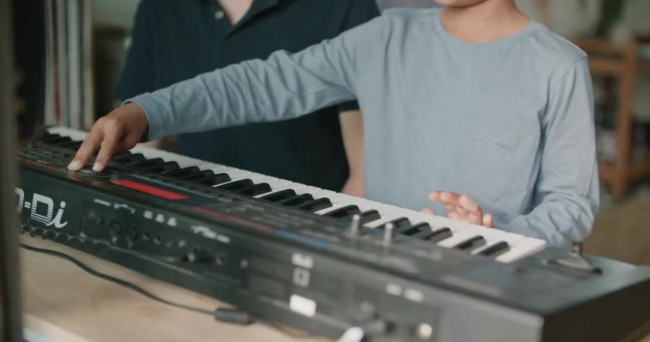 A father is teaching his son to play the piano