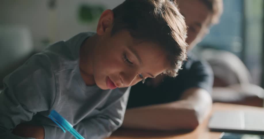 Father and son doing homework on coffee table