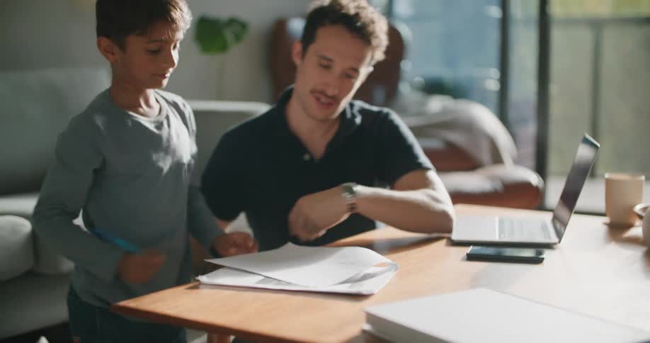 A boy smiles as his father explains a homework problem