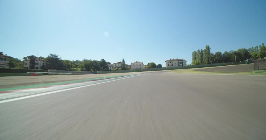 A road at a race track with a neighborhood in the background