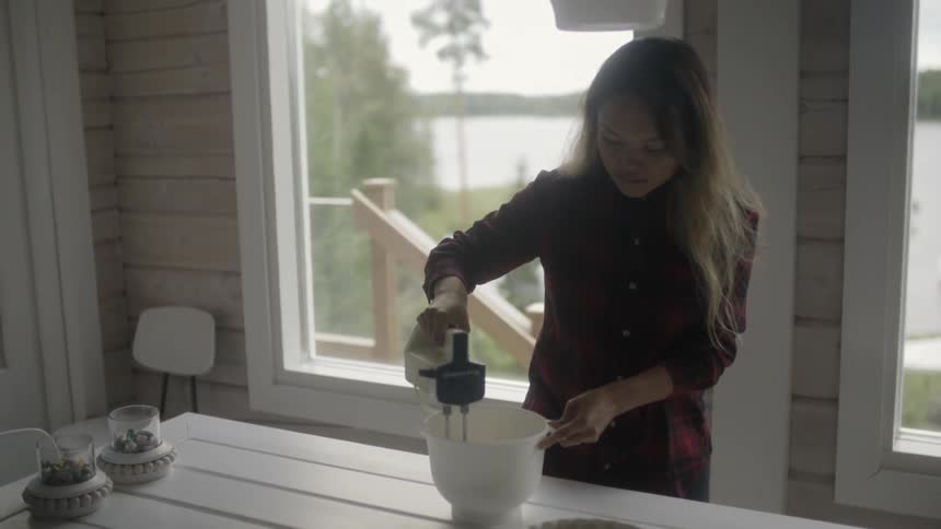 A woman using a hand mixer to mix something in a bowl