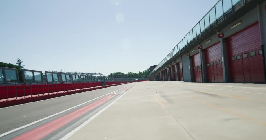 The outer edge of a race track is lined with garages with bright red doors
