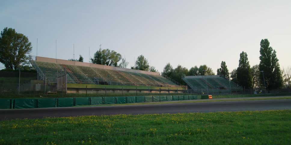 A stadium with bleachers with trees the sky and clouds in the background