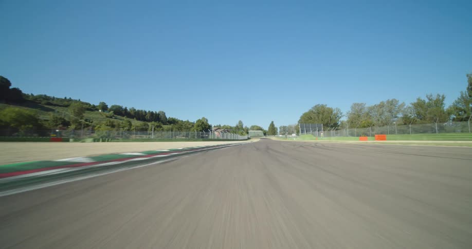 A racetrack surrounded by fences with trees the sky and clouds in the background
