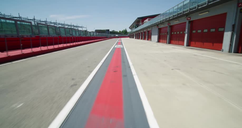 A racetrack next to a fence with trees the sky and clouds in the background