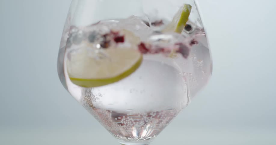 Slices of lemon falling over a ball of ice inside a wine glass