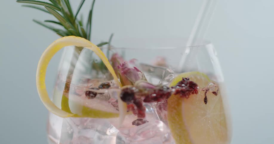 An ice cube is dropped in a glass of fruit water