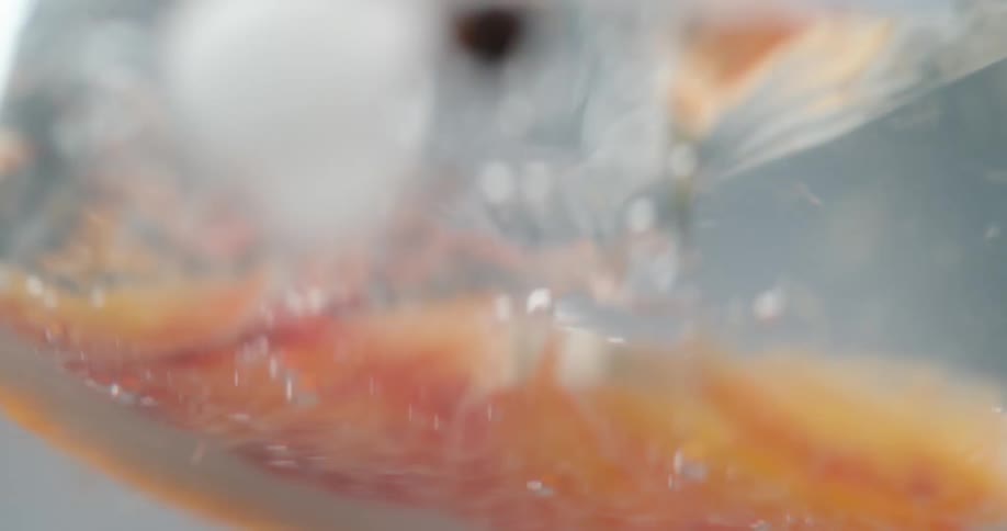 An orange slice drops in to a beverage