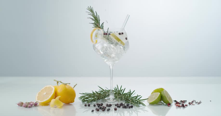 Clear crystal water pouring over ice cubes and lemon slices in a cocktail inside a glass or goblet